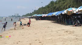 Thai people relaxing on a beach and in the ocean on a hot sunny day in Thailand.