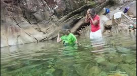 Swimmer stumbles while carrying rock underwater with friend