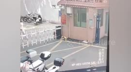 Chinese woman tries climbing over car park barrier.... but it lifts her up and pins her to wall