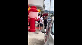 Inflatable God of Wealth tickles Chinese man's armpit during group photo