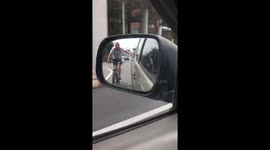 Cyclist hitches a ride by holding onto pickup truck