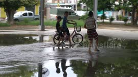 Thai children have great simple fun playing in a flooded sports hall.