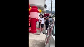 Inflatable God of Wealth tickles Chinese man's armpit during group photo