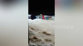 Raging floodwaters surge across street during Several Tropical Storm Trami