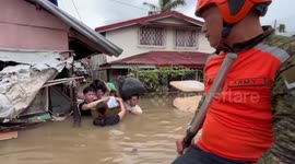 Soldiers carry infant in basin across flood during Tropical Storm Trami