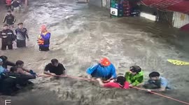 Volunteers help resident cross raging floodwaters during Tropical Storm Trami