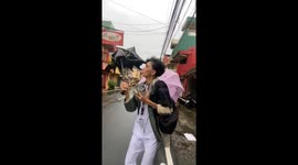 Strong winds challenge people with umbrellas in Lucban, Philippines