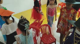Group of adorable children wearing Halloween costumes playing music chair game