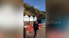 Woman and dog narrowly escaped a fallen cliff fall onto beach huts