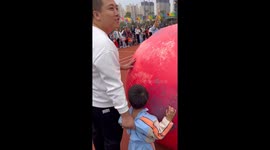 Parents and children push huge balls at school sports day