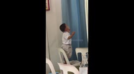 Toddler holds his hands aloft as he prays at church