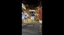 Street food seller carries spring rolls on his head while amusing locals