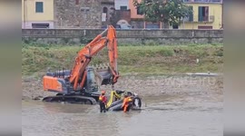Firemen remove car swept into river during storm in Italy