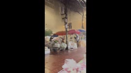 Street vendors hold umbrellas during rainstorm