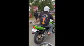 Motorcyclist rides with cat on fuel tank in Arga Makmur, Indonesia