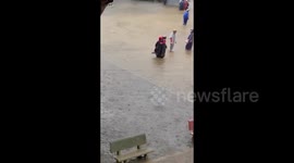 The moment a mother carried her little girl on her back through floodwaters to go to school