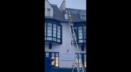 Firefighter attaches rope to top floor of Brixton building while atop multi-storey ladder
