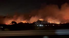 Smoke and flames from the Mountain Fire fill the sky near Santa Paula, California