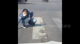 Chinese woman clears glass shards from road during red light and is rewarded with cash prize for her thoughtful act
