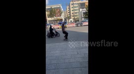 Humorous scene as man rides tiny bike with handlebars far above his head