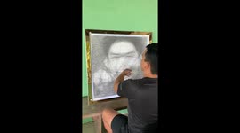 Artist loops strings around board to make string portrait