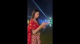 Firework flies from woman's hand as she poses at Buddhist festival