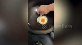Man cooks stir-fry in a hot sizzling wok using only his bare hands