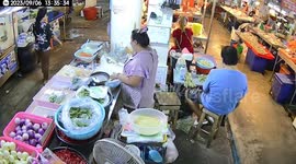 Market vendor blocks rat’s path with his foot away from stall
