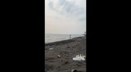 Schoolgirl practices javelin throwing on beach