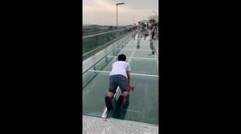 Boyfriend with fear of heights crawls across glass bridge as his legs tremble