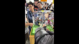 Young men strokes toy figures to melt them out of large ice block