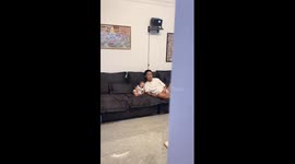 Baby wearing face mask sits next to father on sofa