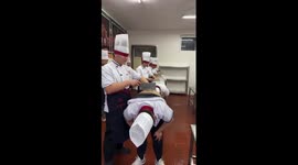 Trainee chefs practice cutting skills by slicing vegetables on their colleagues' backs