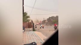 Children flee from storm whipping up dirt and dust on street