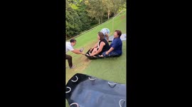 Two ladies fall while sliding on grass in Kanchanaburi, Thailand