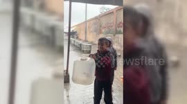 Gaza: Child Collects Rainwater at a Gaza Shelter Amid Dire Conditions
