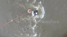 Helicopter rescues two men from roof of car battered by floodwaters on bridge
