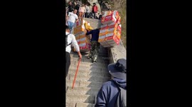 Worker carries dozens of boxes up steps at mountain in China