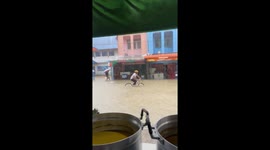 Determined cyclist pedals through flooded road in Thailand