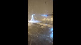 Ground worker removes snow from plane in South Korea