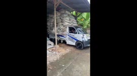 Mini truck’s overloaded cargo spills with guy on top in Kisaran, North Sumatra, Indonesia