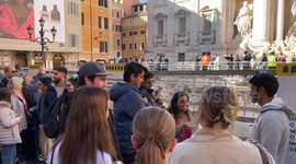 A tourist throws a coin into the basin of water that was installed at the Trevi Fountain during the cleaning work for the Jubilee.