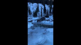 Jeep crosses frozen river after ice breaks in Nordegg, Alberta, Canada