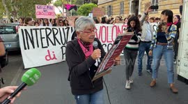 A feminist activist reads information from a sign during the march in the demonstration for the right to abortion organized by the Not One Less movement in Rome.
