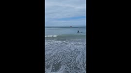 Inflatable dragon boat topples over dumping tourists into the surf