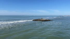 The statue of Neptune and its cliff surrounded by calm seas on a sunny October day at Lido di Ostia in Rome.