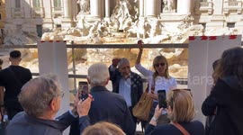 Tourists throw coins over the fence built around the Trevi Fountain during cleaning work due to the proximity of the Jubilee in Rome.