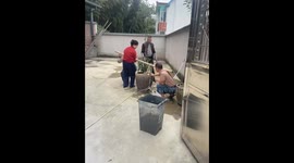 Four people attempt to lift a large vase using a bamboo stick in Zhejiang, China