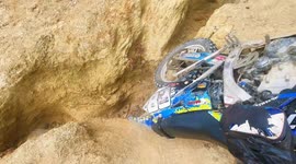 Off road dirt rider falls while trying to ride up tricky terrain