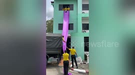 Clever schoolkids slide books down purple fabric from building's third floor